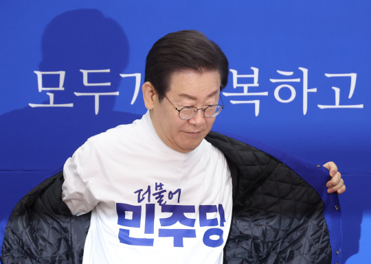 24일 국회에서 열린 더불어민주당 새 PI 선포식에서 이재명 대표가 새 로고가 프린트 된 옷으로 환복하고 있다. 연합뉴스.